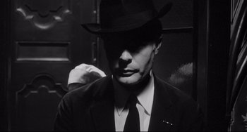 Movie still from “8½” (1963), directed by Federico Fellini – A black and white photo of a man in a suit and hat; Close Up shot, Over the shoulder angle