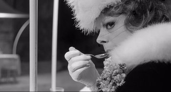 Movie still from “8½” (1963), directed by Federico Fellini – A woman in a fur hat eating something with a spoon; Close Up shot, Over the shoulder angle