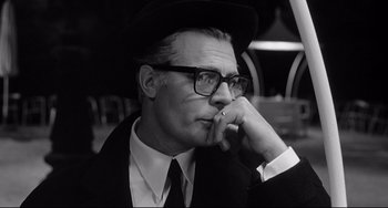 Movie still from “8½” (1963), directed by Federico Fellini – An older man wearing glasses and a hat; Close Up shot, Low angle