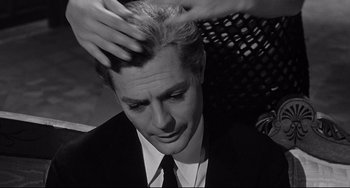 Movie still from “8½” (1963), directed by Federico Fellini – A man in a suit and tie getting his hair combed; Close Up shot, Over the shoulder angle