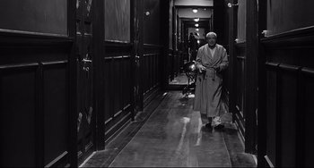 Movie still from “8½” (1963), directed by Federico Fellini – An old man walking down a hallway with a cane; Wide shot, High angle