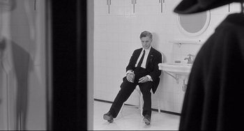 Movie still from “8½” (1963), directed by Federico Fellini – A black and white photo of a man sitting in a bathroom; Wide shot, High angle