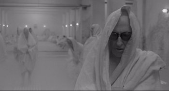 Movie still from “8½” (1963), directed by Federico Fellini – An older woman wearing sunglasses and a white robe; Medium shot, High angle