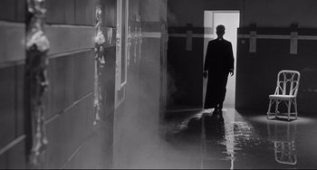 Movie still from “8½” (1963), directed by Federico Fellini – A man walking down a hall way in a building; Wide shot, Low angle