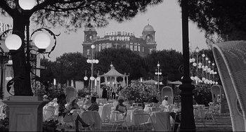 Movie still from “8½” (1963), directed by Federico Fellini – A black and white photo of people sitting at tables outside; Extreme Wide shot, Low angle