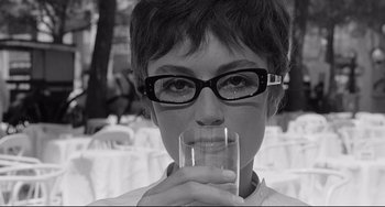 Movie still from “8½” (1963), directed by Federico Fellini – A woman wearing glasses drinking a glass of water; Close Up shot, Low angle
