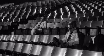 Movie still from “8½” (1963), directed by Federico Fellini – Two men sitting in seats in an empty stadium; Wide shot, High angle