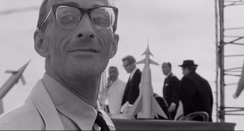 Movie still from “8½” (1963), directed by Federico Fellini – Black and white photograph of a man in front of a group of men; Close Up shot, Low angle