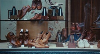 Movie still from “9 to 5” (1980), directed by Colin Higgins – Many different types of shoes on display; Wide shot, Low angle