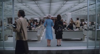 Movie still from “9 to 5” (1980), directed by Colin Higgins – Two women are standing in a room with a bunch of people; Wide shot, High angle