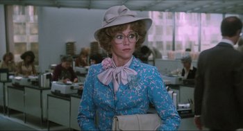 Movie still from “9 to 5” (1980), directed by Colin Higgins – A woman in a blue dress and a white hat; Medium shot, Over the shoulder angle