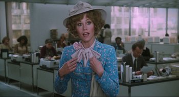Movie still from “9 to 5” (1980), directed by Colin Higgins – A woman in a blue suit and a white hat; Medium shot, Over the shoulder angle