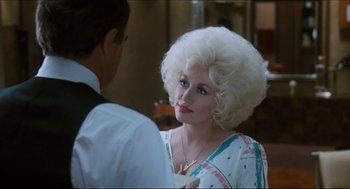 Movie still from “9 to 5” (1980), directed by Colin Higgins – A woman in a white wig talking to a man in a white suit; Close Up shot, Over the shoulder angle