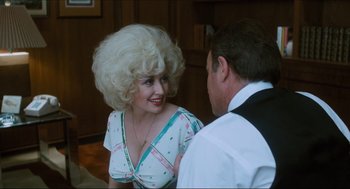 Movie still from “9 to 5” (1980), directed by Colin Higgins – A man and a woman wearing wigs talking to each other; Medium shot, Over the shoulder angle