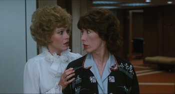 Movie still from “9 to 5” (1980), directed by Colin Higgins – Two women standing next to each other in front of a building; Close Up shot, Over the shoulder angle
