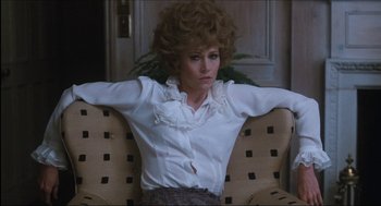 Movie still from “9 to 5” (1980), directed by Colin Higgins – A woman sitting in a chair with her arms behind her head; Medium shot, Low angle