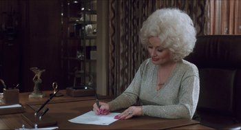 Movie still from “9 to 5” (1980), directed by Colin Higgins – An older woman writing on a piece of paper; Medium shot, High angle