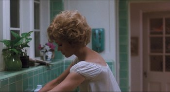 Movie still from “9 to 5” (1980), directed by Colin Higgins – A woman in a white shirt is washing her hands; Medium shot, Over the shoulder angle