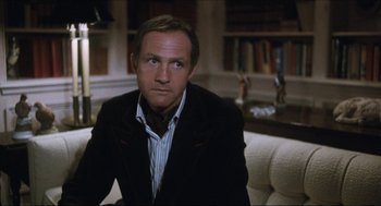 Movie still from “9 to 5” (1980), directed by Colin Higgins – A person sitting on a couch in a living room; Close Up shot, Low angle