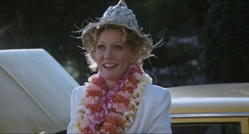 Movie still from “9 to 5” (1980), directed by Colin Higgins – A woman wearing a straw hat and a flower lei; Close Up shot, Low angle