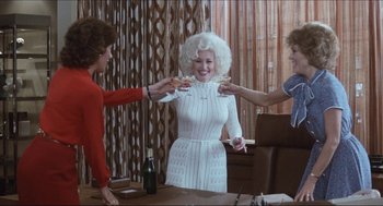 Movie still from “9 to 5” (1980), directed by Colin Higgins – Three women are toasting with wine in a room; Medium shot, Over the shoulder angle