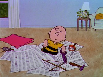 Movie still from “A Boy Named Charlie Brown” (1969), directed by Bill Melendez – A charlie brown cartoon character sitting on top of a pile of papers; Extreme Wide shot, Overhead angle