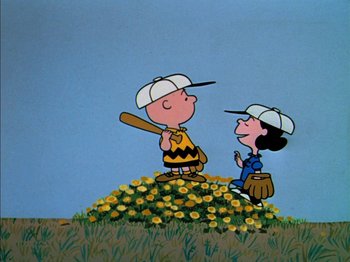 A charlie brown and a peanuts character are standing in a field of yellow flowers