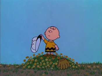 Movie still from “A Boy Named Charlie Brown” (1969), directed by Bill Melendez – A charlie brown character holding a shoe in a field of yellow flowers; Medium shot, Low angle