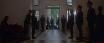 Movie still from “A Bridge Too Far” (1977), directed by Richard Attenborough – A group of men standing in front of an open door; Wide shot, Low angle