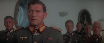 Movie still from “A Bridge Too Far” (1977), directed by Richard Attenborough – A man in a military uniform stands in front of another man; Close Up shot, Low angle