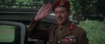 Movie still from “A Bridge Too Far” (1977), directed by Richard Attenborough – A man in a military uniform saluting in front of a bus; Medium shot, Low angle