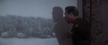 Movie still from “A Bridge Too Far” (1977), directed by Richard Attenborough – A man standing in front of a car in the snow; Medium shot, Over the shoulder angle