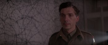 Movie still from “A Bridge Too Far” (1977), directed by Richard Attenborough – A man in a military uniform standing in front of a wall; Close Up shot, Low angle
