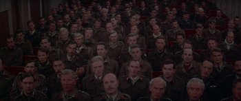Movie still from “A Bridge Too Far” (1977), directed by Richard Attenborough – A large group of men in uniform sitting in a room; Wide shot, High angle