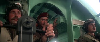 Movie still from “A Bridge Too Far” (1977), directed by Richard Attenborough – A man in a red hat is holding onto a pole; Medium shot, Low angle