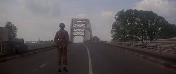 Movie still from “A Bridge Too Far” (1977), directed by Richard Attenborough – A man standing on the side of a bridge; Wide shot, Low angle
