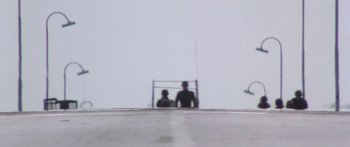 Movie still from “A Bridge Too Far” (1977), directed by Richard Attenborough – Two people sitting on a bench looking out at the sky; Extreme Wide shot, High angle