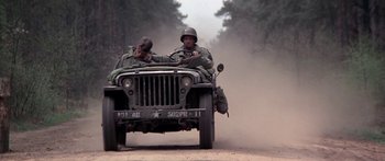 Movie still from “A Bridge Too Far” (1977), directed by Richard Attenborough – Two soldiers sitting in the back of an army vehicle; Wide shot, Low angle