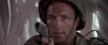 Movie still from “A Bridge Too Far” (1977), directed by Richard Attenborough – A person holding a gun; Close Up shot, Low angle