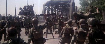 Movie still from “A Bridge Too Far” (1977), directed by Richard Attenborough – A group of soldiers are standing on a bridge; Wide shot, High angle