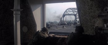 Movie still from “A Bridge Too Far” (1977), directed by Richard Attenborough – A train traveling on tracks near a bridge; Wide shot, High angle