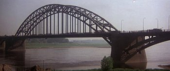 Movie still from “A Bridge Too Far” (1977), directed by Richard Attenborough – A bridge over a body of water near a body of water; Extreme Wide shot, High angle
