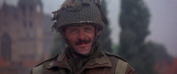 Movie still from “A Bridge Too Far” (1977), directed by Richard Attenborough – A man wearing a military uniform and a helmet; Close Up shot, Low angle