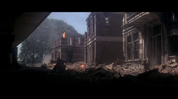 Movie still from “A Bridge Too Far” (1977), directed by Richard Attenborough – A fire is burning in the middle of a destroyed building; Extreme Wide shot, Low angle