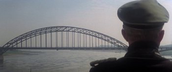Movie still from “A Bridge Too Far” (1977), directed by Richard Attenborough – A bridge over a body of water near a body of water; Extreme Wide shot, Low angle