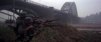 Movie still from “A Bridge Too Far” (1977), directed by Richard Attenborough – A group of men in military uniforms with guns; Wide shot, High angle