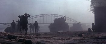 Movie still from “A Bridge Too Far” (1977), directed by Richard Attenborough – An image of a tank driving down a road in the fog; Extreme Wide shot, High angle