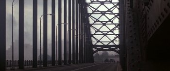 Movie still from “A Bridge Too Far” (1977), directed by Richard Attenborough – A bridge that has a metal structure on top of it; Extreme Wide shot, Low angle