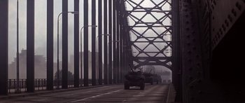 Movie still from “A Bridge Too Far” (1977), directed by Richard Attenborough – A truck driving across a bridge in the middle of the day; Extreme Wide shot, High angle