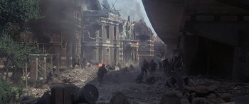 Movie still from “A Bridge Too Far” (1977), directed by Richard Attenborough – A group of people are running through the ruins; Extreme Wide shot, High angle